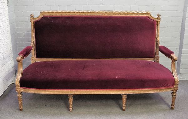 A Louis XVI style, gilt framed open arm sofa, with bow seat on tapering fluted supports, 184cm wide x 109cm high.