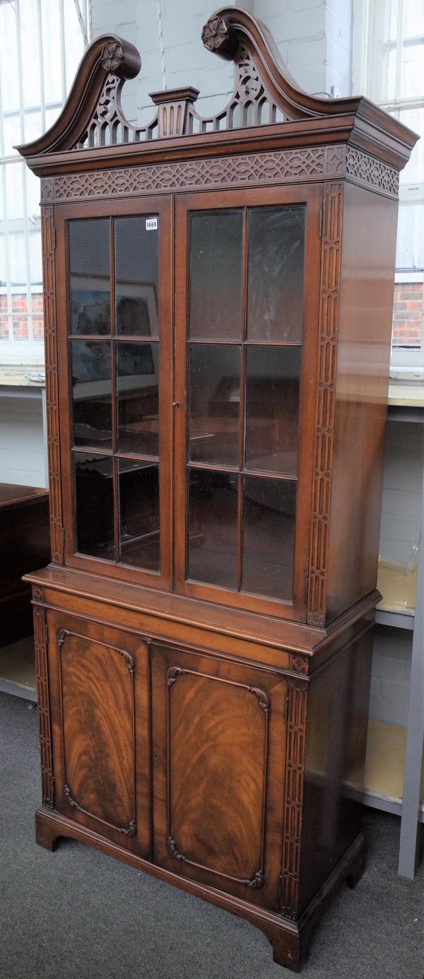 A George III style bookcase cabinet, the broken swan neck cornice over a par of glazed doors and cupboard base, on bracket feet, 90cm wide x 206cm hig