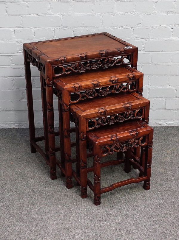 A nest of four Chinese hardwood occasional tables, with parcel gilt and floral carved frieze, the larger 51cm wide x 66cm high, (4).