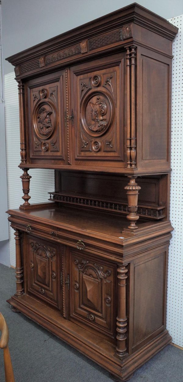 A 19th century French walnut buffet, the pair of upper doors relief carved with facing portrait figures over a pair of drawers and lower cupboards, 15