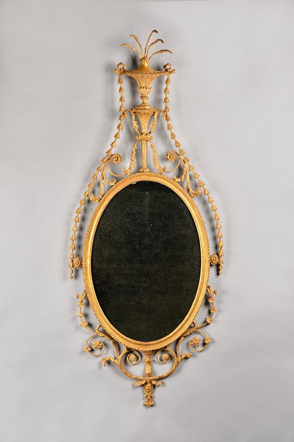 A George III gilt framed wall mirror, with stylized urn crest above oval mirror plate, within a foliate scroll border, 62cm wide x 152cm high. Illustr