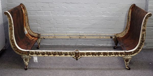 An early 20th century parcel gilt white painted, cast iron scroll end child's bed, relief cast with flowers, 200cm wide x 84cm high.