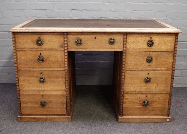 An early 20th century bleached oak writing desk with nine drawers about the knee, flanked by split bobbin mounts, 124cm wide x 76cm high.