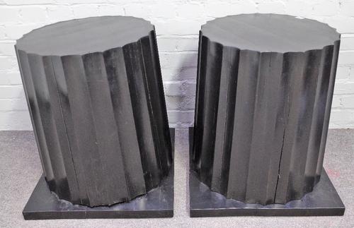 A pair of ebonised hardwood columns, with fluted bodies and square bases, 59cm wide at base x 63cm high, (2).