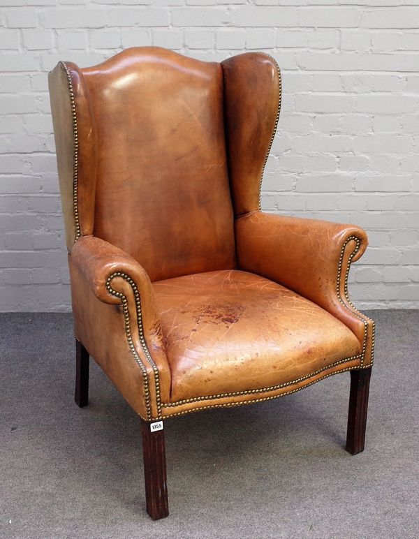 A George II style studded brown leather upholstered wingback on channelled square supports, 84cm wide x 93cm high.