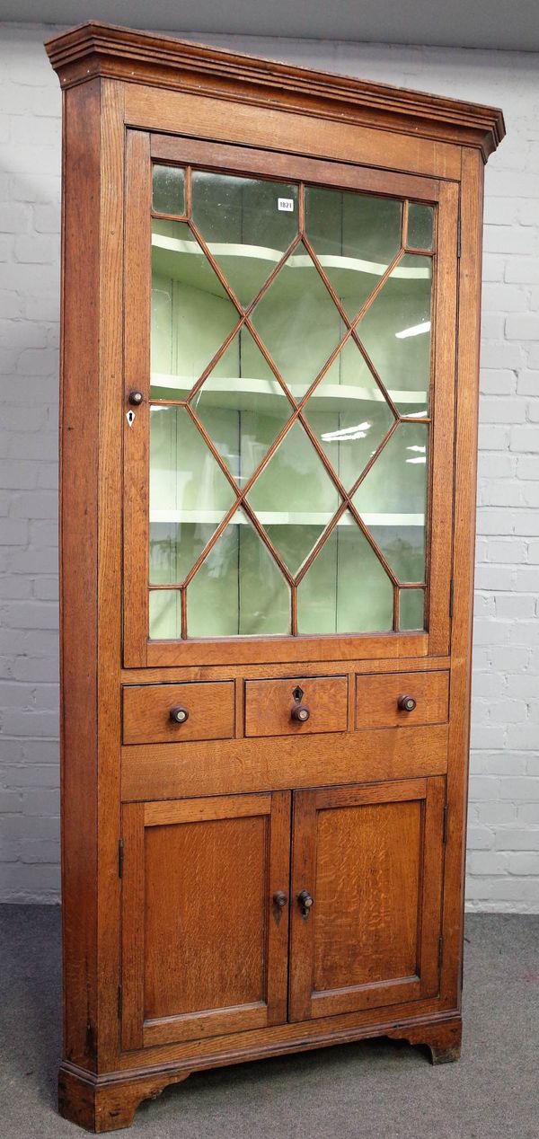 An 18th century oak floor standing corner display cabinet, the astragal glazed door over three drawers and a pair of cupboards, 99cm wide x 206cm high