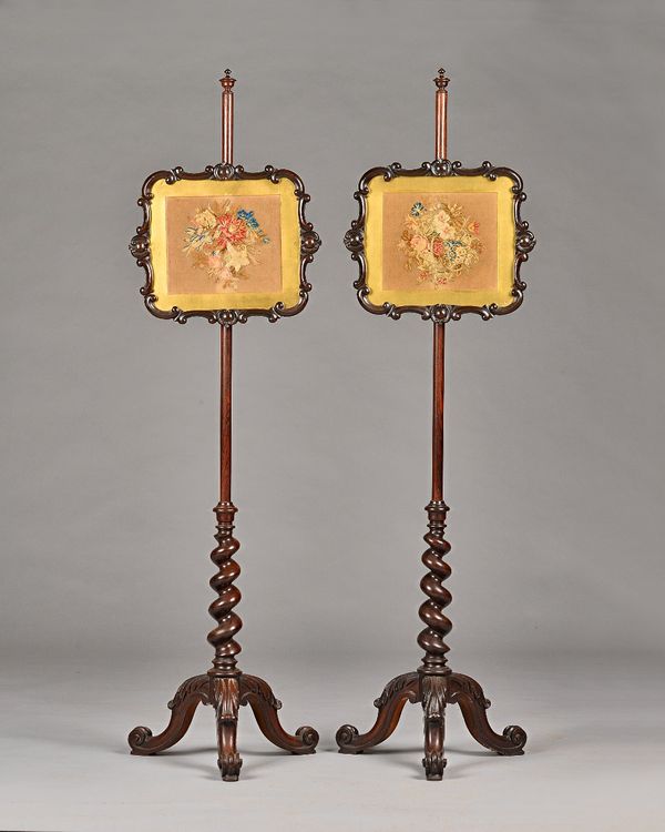 A pair of Victorian rosewood pole screens on barleytwist columns and three scroll supports, 145cm high, the screens 40cm wide. Illustrated.