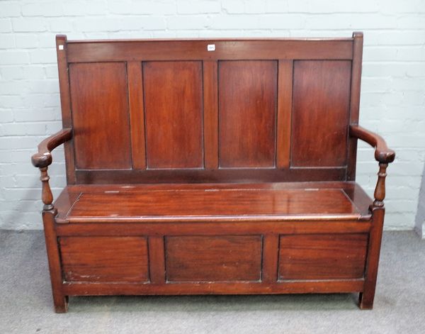 An Arts & Crafts mahogany box seat settle, the four panelled back over open arms, the lift seat over triple panelled front, 148cm wide x 114cm high.