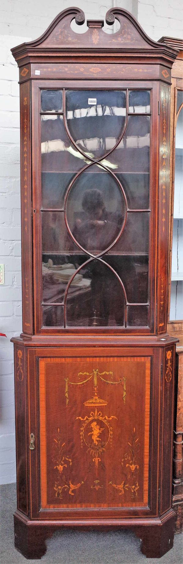 An Edwardian marquetry inlaid mahogany floor standing corner display cabinet, the single astragal glazed door over cupboard on bracket feet, 69cm wide