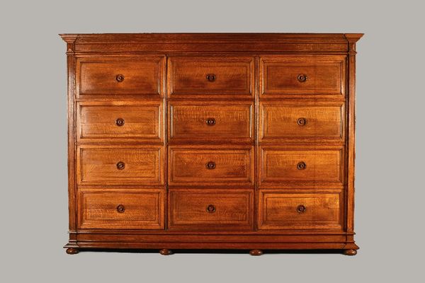 An early 20th French oak locker cabinet with three rows of four up and over doors resting on plinth base, 280cm wide x 205cm high. Illustrated.