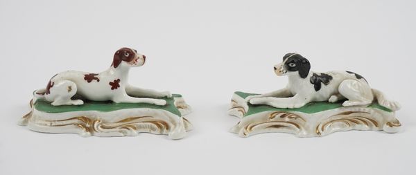 A pair of Staffordshire porcelain figures of a brown and white pointer and a black and white setter, circa 1830-40, each modelled recumbent on a green