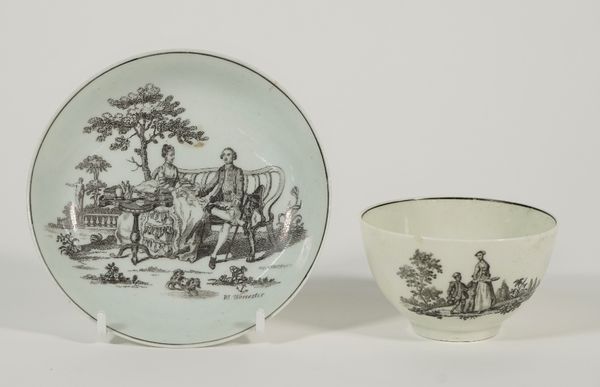 A Worcester porcelain teabowl and a matched saucer, circa 1760-65,  each transfer printed in black with 'The Tea Party', the saucer with an anchor and