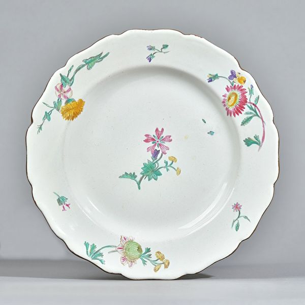 Four Marseille faience plates, circa 1765, of silver shape, painted with scattered flowers and sprigs, 25cm diameter, (4). Provenance: Sotheby's Londo