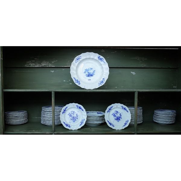 A Tournai porcelain blue and white table service, 19th century, each piece painted with flowering plants and flower sprays inside a scroll and basket