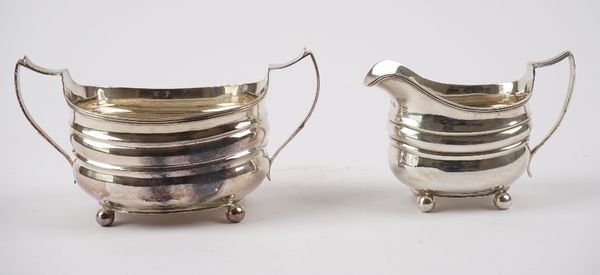 A George III silver twin handled sugar bowl, raised on four spherical feet and a George III matching silver milk jug, of helmet shaped form, raised on