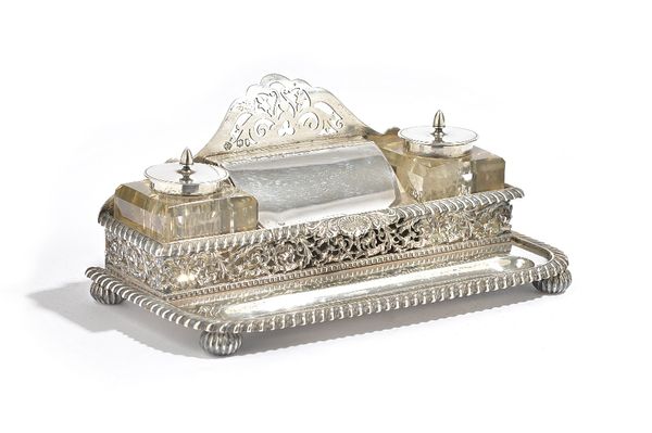 A Victorian silver shaped rectangular twin bottle inkstand, having a central hinge lidded box compartment and a pen rest, within gadrooned and pierced