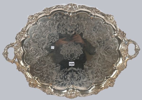 A Victorian plated on copper shaped oval twin handled tray, engraved with a coat of arms to the centre, within a scroll engraved surround and with a f