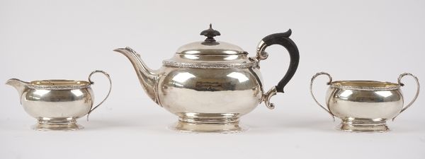 A silver three piece tea set, comprising; a teapot with black fittings, a twin handled sugar bowl and a milk jug, each piece of oval form, with a deco