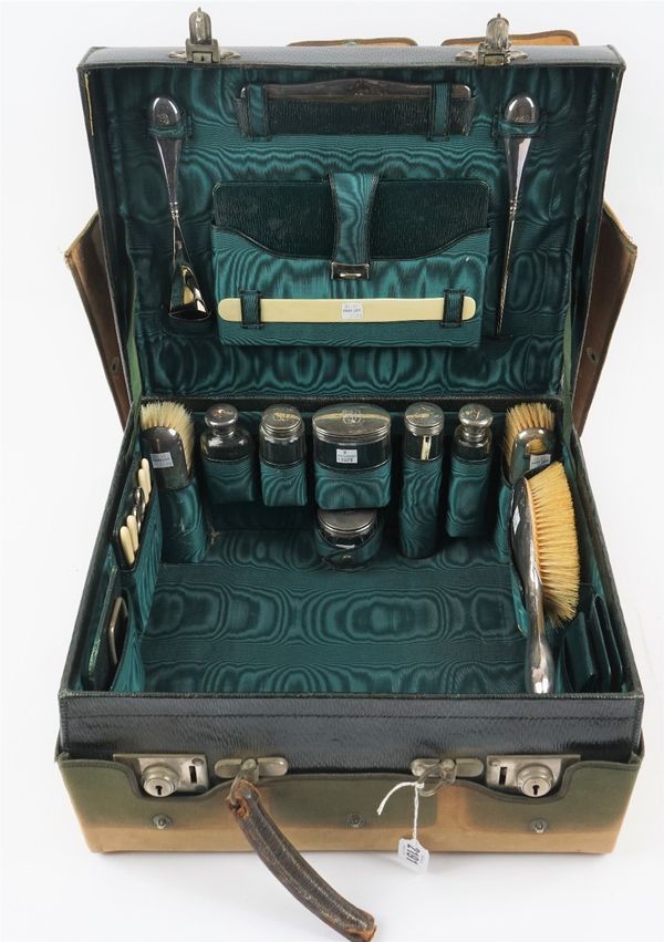 A lady's silver mounted travelling toilet cum dressing set, the case opening to reveal various fittings, including six glass toilet bottles and jars,