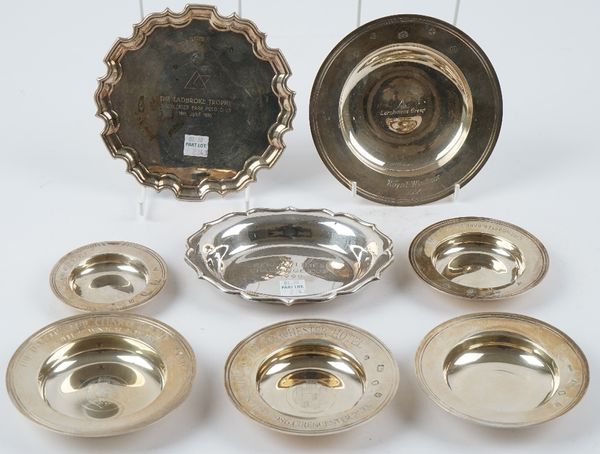 Six silver Armada style dishes in varying sizes, a shaped oval trinket dish and a shaped circular card tray, mostly presentation inscribed, combined w