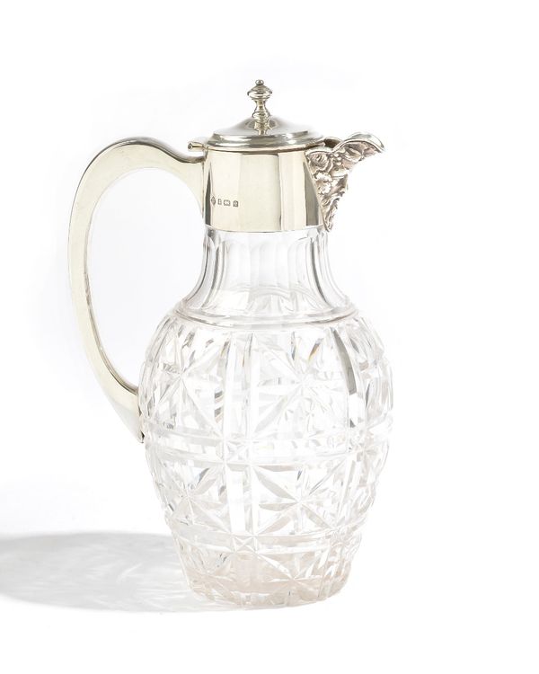 A silver mounted faceted glass claret jug, the spout formed as a Bacchus mask, the hinged lid having a turned finial, Birmingham 1904, height 24cm. Il