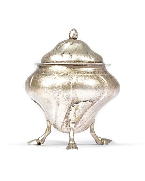 A foreign tea caddy, with a detachable cover, having widely fluted decoration, raised on three hoof shaped feet, the cover with a bud finial, height 1