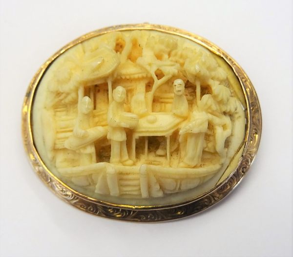 A gold mounted Cantonese carved ivory oval pendant brooch, carved as various figures, a house and trees, the gold surround with scroll engraved decora