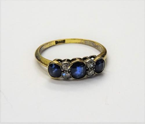 A gold, sapphire and diamond ring, mounted with three oval cut sapphires and with two pairs of cushion shaped diamonds mounted at intervals, detailed