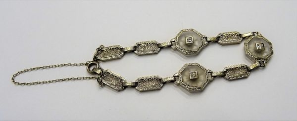 A two colour gold and diamond bracelet, formed as a row of filigree pierced panel shaped links and with three octagonal diamond set links at intervals