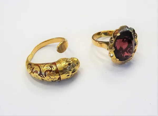 A gold and red enamelled ring, of expanding form, designed as a lion's head, gross weight 11 gms and a gold ring, claw set with an oval cut garnet wit