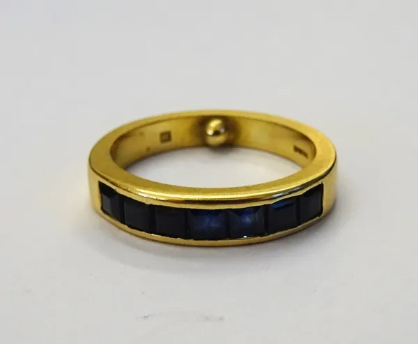 An 18ct gold and sapphire half hoop ring, channel set with a row of seven square cut sapphires by Allan Christensen, Petworth, ring size K and a half,