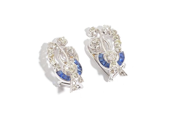 A pair of sapphire and diamond earclips, each in an openwork curved and spray design, mounted with seven calibre cut sapphires and otherwise set with