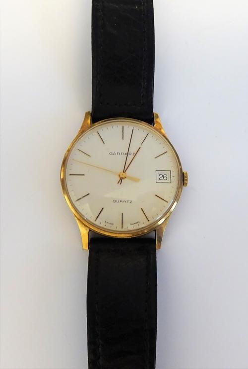 A Garrard Quartz 9ct gold circular cased gentleman's wristwatch, the signed silvered dial with baton shaped numerals, date of the month aperture and w