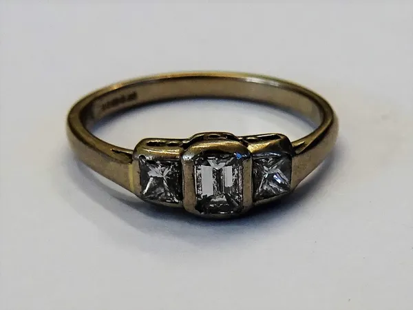 An 18ct white gold and diamond set three stone ring, mounted with a rectangular emerald cut diamond to the centre, between two princess cut diamonds,