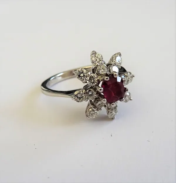 An 18ct white gold, ruby and diamond ring, in an eight pointed star shaped design, mounted with the square emerald cut ruby to the centre, in a radiat