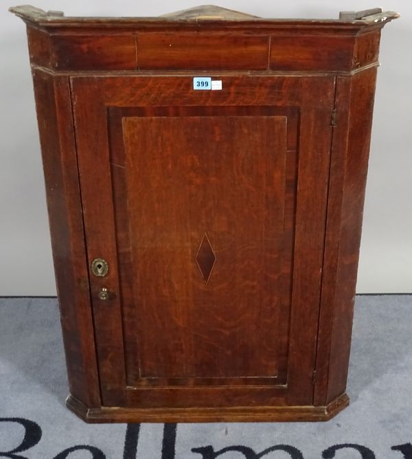 An 18th century oak and mahogany hanging corner cupboard, 69cm wide x 96cm high. B3