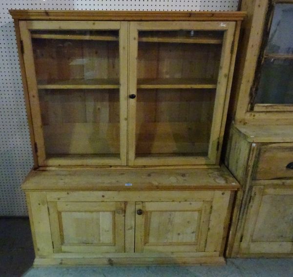 A 20th century pine bookcase with two glazed doors over cupboard base, 130cm wide x 157cm high.   A2