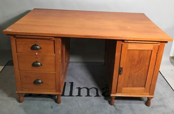 A mid-20th century oak pedestal desk with three small drawers and cupboard base on turned supports, 138cm wide.   B3