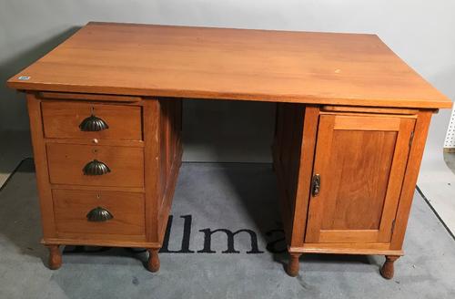 A mid-20th century oak pedestal desk with three small drawers and cupboard base on turned supports, 138cm wide.   B3