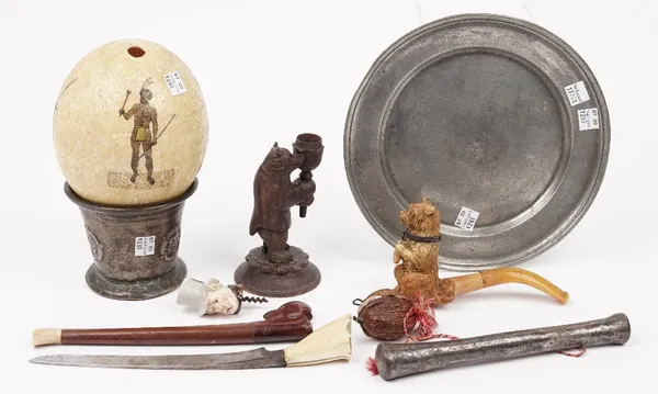 A group of collectables including; a Meershaum pipe carved as a begging dog, 9cm high, an ostrich egg painted with a native warrior, a miniature porce