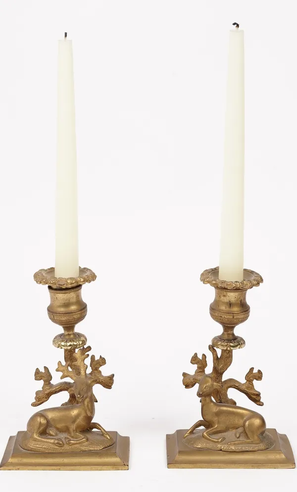 A pair of Regency style gilt bronze candlesticks with recumbant stag and deer to the stepped rectangular base, 14cm high, (2).