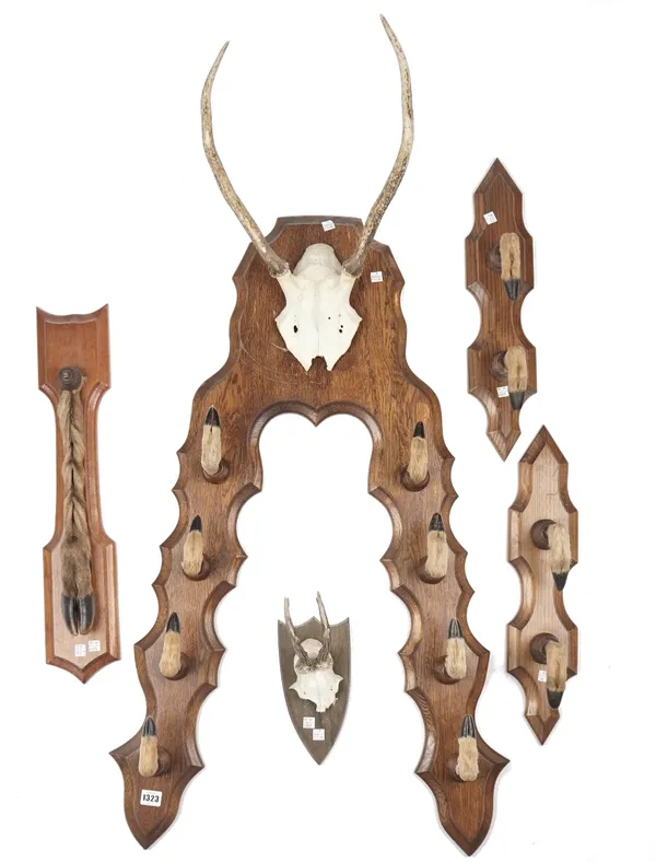 Taxidermy; an oak framed four tier gun rack with applied deer hooves and antler skull surmount, 120cm high, a smaller similar two tier gun rack and tw