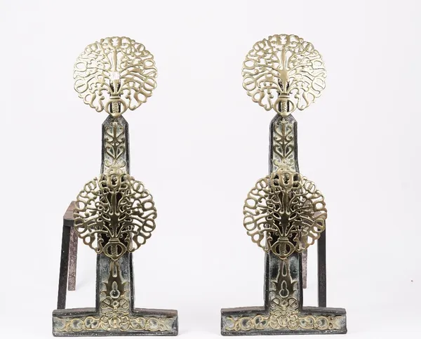 A pair of Arts and Crafts brass and wrought iron fire dogs, in the manner of The Artificier's Guild and Edward Spencer, each with two pierced circular