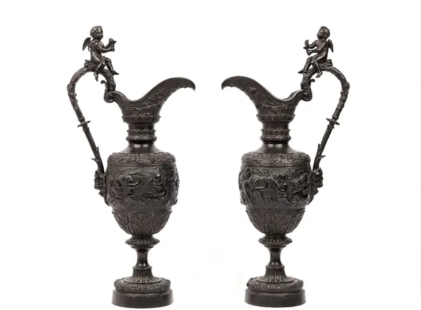 A pair of bronze ewers, after the antique, late 19th century, cast with bacchanalian scenes of fruiting vines, putti and cherubs in various pursuits,