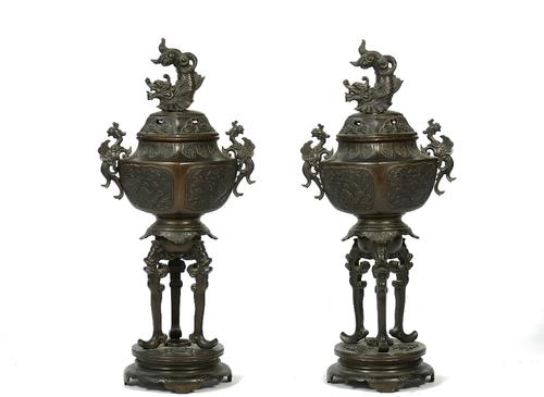 A pair of Japanese bronze vases and covers, early 20th century, each with dragon finial and pierced cover, raised on three long supports over a shaped