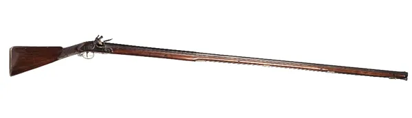 An 18th century flintlock rifle with tapering steel barrel, 148cm, plain steel lockplate, chequered walnut stock and brass mounts, 190cm overall.