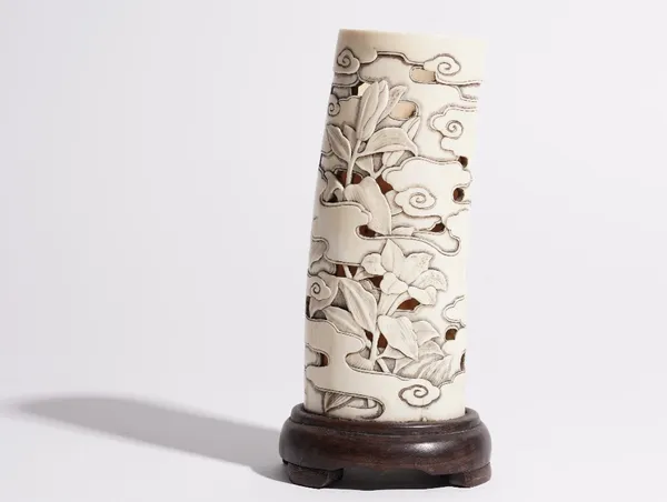 A Japanese ivory tusk vase, Meiji period, pierced and carved with a bird amongst flowers, 14.5cm. high, wood stand.