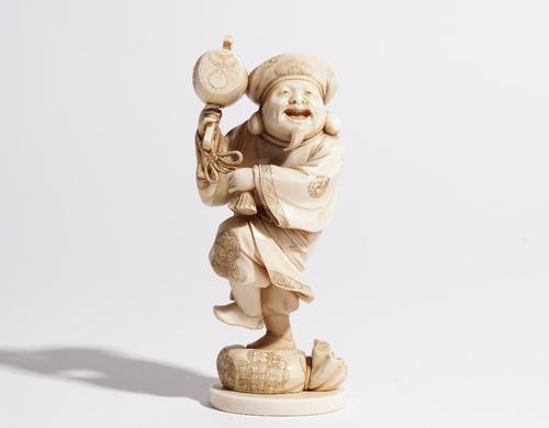 A Japanese ivory okimono of Daikoku, Meiji period, carved standing holding a mallet, his right foot resting on a sack, signed on red lacquer reserve,