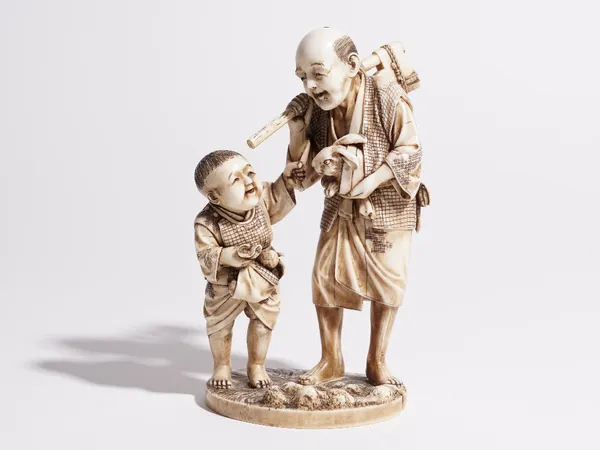 A Japanese ivory okimono of a man and boy, both standing, the man carrying an axe and hare, signed, 15cm high.