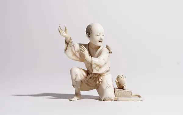 A Japanese ivory okimono of a rat catcher, Meiji period, carved kneeling with a rat scampering across his shoulder, a cat standing on a trap beside, s